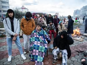 Earthquake survivors sit around a fire in Iskenderun Turkey