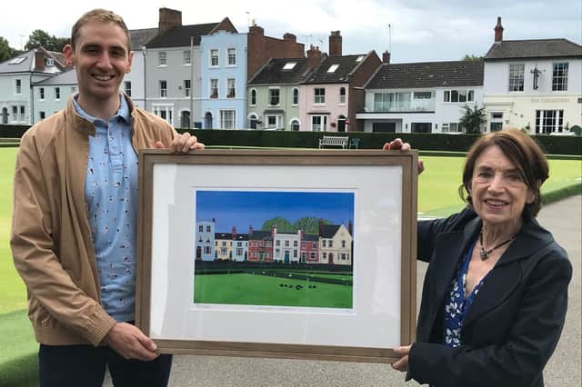 Robin Gillam receives the prize from Barbara Lynn, chair of the Leamington Society. The picture, generously donated by the artist Clive Engwell, depicts a scene across a bowling green with a familiar backdrop of houses similar to that seen from the location of the presentation.