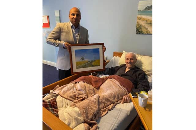 Bromson Hill Nursing Home owner, Ram Mahendran gifting long-standing resident, Derek Ogden, a print of the Chesterton Windmill. Photo supplied