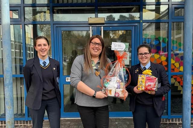 Alex Pearson, community fundraiser at Leamington Morrisons, presents the hamper to Charlotte and Grace at Henley School. Photo supplied