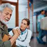 A white haired man is comforted by a brown haired doctor