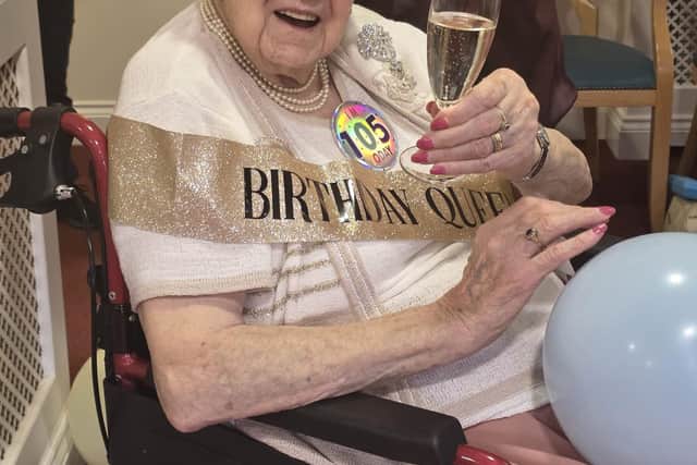Cheers! Marjorie raises a glass with friends and family to mark her 105th birthday.