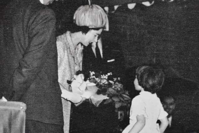 Five-year-old Ruth Wallis presents the Queen with roses.