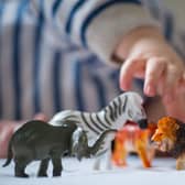 A preschool age child plays with plastic toy animals.