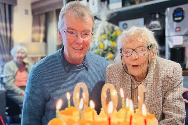 Audrey Vincett, pictured with her son Chris, blows out the candles on her 100th birthday cake.