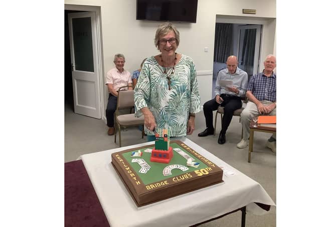 Gail Hart, one of the founding members of Kenilworth Bridge Club, cuts the cake to celebrate the club's 50th anniversary.