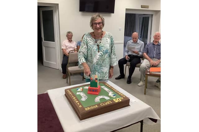 Gail Hart, one of the founding members of Kenilworth Bridge Club, cuts the cake to celebrate the club's 50th anniversary.