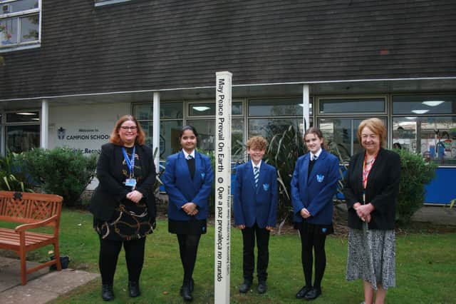 Campion School pupils place the Peace Pole outside the school's entrance with Julie Gardner, Head of RE (left), and Margaret Morley, Rotarian (right). Picture supplied.