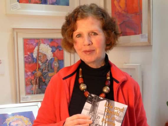Susan Moore in her studio with her book - the artwork in the background is hers.