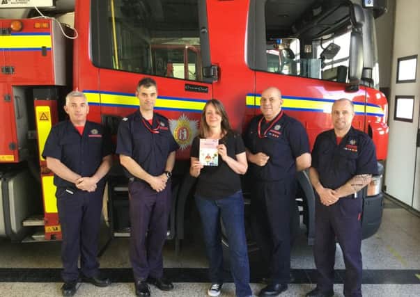 Lucy Bergonzi presenting a fire crew in Leamington with the book 'Belonging'. Photo provided by Warwickshire County Council.