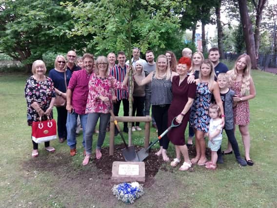 Andy Parker's friends and family next to his newly-replanted tree and memorial stone. His sisters Julie (front row, third from left), Lindy (front row, fourth from left) and Caroline (front row, fifth from right) all helped campaign for the replanting