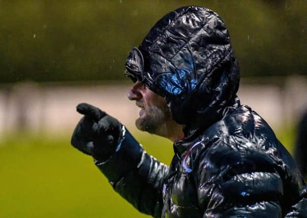 A very wet manager Carl Adams peers through the driving rain on Saturday