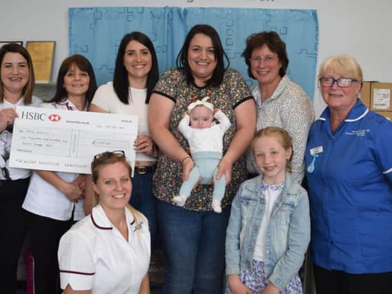 Laura Worsley, baby Ivy and family members present the cheque to the UHCW Charity.