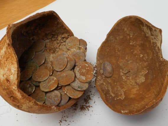 Some of the Roman coin hoard and the pot they were found in. Photo by Warwickshire County Council.