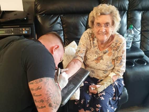 Tattoo artist Matty Gardner inks the tattoo onto the wrist of Hilda West