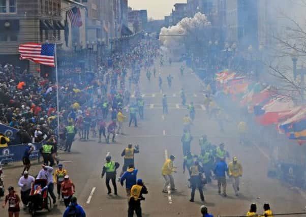 People react as an explosion goes off near the finish line of the 2013 Boston Marathon in Boston, Monday, April 15, 2013. Two explosions went off at the Boston Marathon finish line on Monday, sending authorities out on the course to carry off the injured while the stragglers were rerouted away from the smoking site of the blasts. (AP Photo/The Boston Globe, David L Ryan)  MANDATORY CREDIT