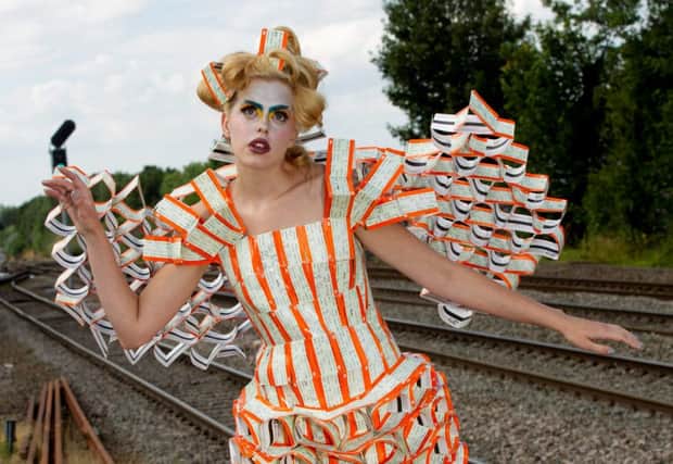 Bruja Estrella Howe models a dress made of train tickets which was designed and made by Aleah Leigh  See Newsteam story NTIDRESS. A fashion designer has created a first class Lady Gaga-style dress - made from thousands of discarded TRAIN TICKETS. Quirky Aleah Leigh, 25, has been designing dresses for two years and has already used recycled materials like crisp packets, playing cards and rubber gloves. Now the self-trained designer has unveiled her latest fashion line - a flowing dress made out of 3,500 used train tickets. Single mum-of-two Aleah came up with the idea while travelling on a Chiltern train to London earlier this year.Staff at Leamington Spa train station helped the designer, who was born in the Warwickshire town, to collect the standard orange and white tickets. She then stapled and Sellotaped them together to create a long dress complete with angel wings on the back and even a head-piece.