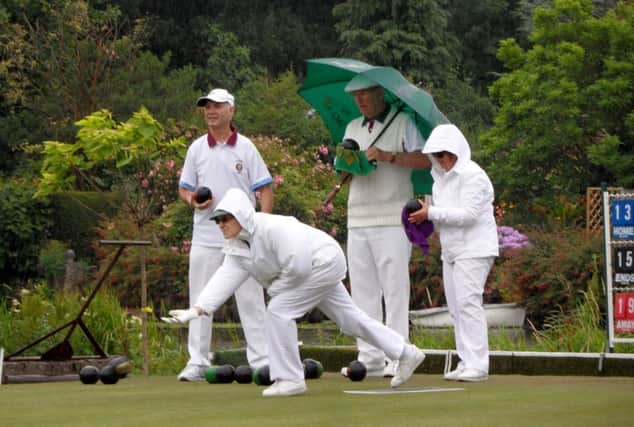 Keeping the woods dry was a major problem for bowlers taking art in the Warwick Town Mixed Triples competition. Here, Janet Allibon sends down a bowl.