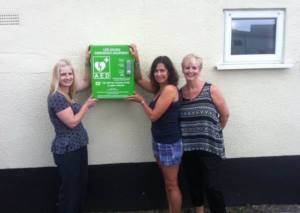 Jackie Prior (right) and Sarah Sabin (centre) unveil the Public access defibrillator at Bishops Tachbrook Sports and Social Club with club stewardess Karen Capehorn.