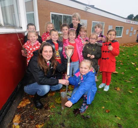 Parent Louise Reading helps her daughter Imogen, 6, to plant a tree with some of year 2 and their teacher Amy Payne getting ready to plant theirs.