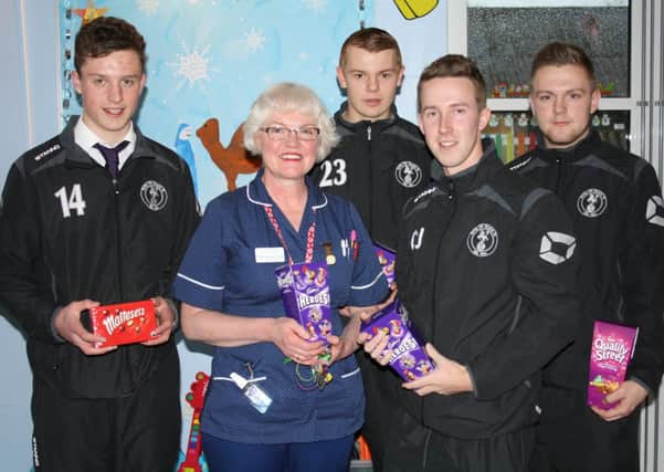 Racing Club Warwick FCs Oliver Jones, Kelsey Purchase, Josh Tiff and James Mudie present chocolates to Paediatric Ward Manager Maggie Ward in the Units Play Room.