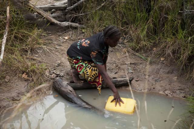 Dimitria Lubinga collects water from an unsafe open well in Habeenzu village in Zambia. Picture by Anna Kari for WaterAid.
