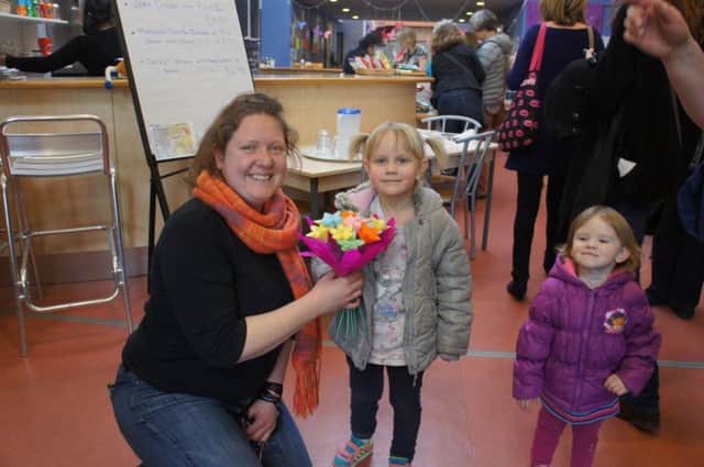 Sydni Centre manager Kate Cliffe being presented with flowers by Olivia Sulkowska, accompanied by her sister Sara, as part of International Women's Day celebrations.