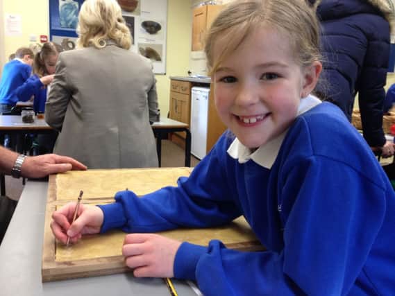 Telford Junior School pupil Nancy Ford tries out Roman writing at Priory House in Warwick.
