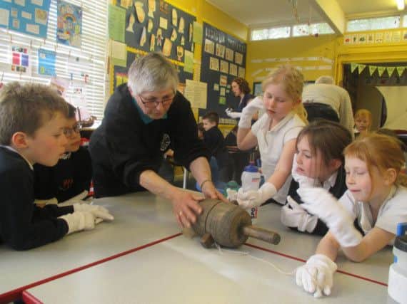 Chedham's Yard volunteer Heather Cox shows some artefacts found in the yard to pupils from Wellesbourne Primary School.