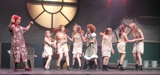 Joanne Murphy as Miss Hannigan with Mollie Dibb as Annie and orphans played by Isabella Fenton, Lauren McCann, Isobel Woodward, Kathryn Ritchie, Tanya Saunders and Carly Furlong.