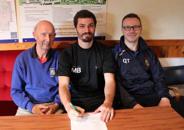 Mark Bellingham puts pen to paper at Banbury Road watched by Bobby Hancocks and Saints boss Quentin Townsend. Picture: David Hucker