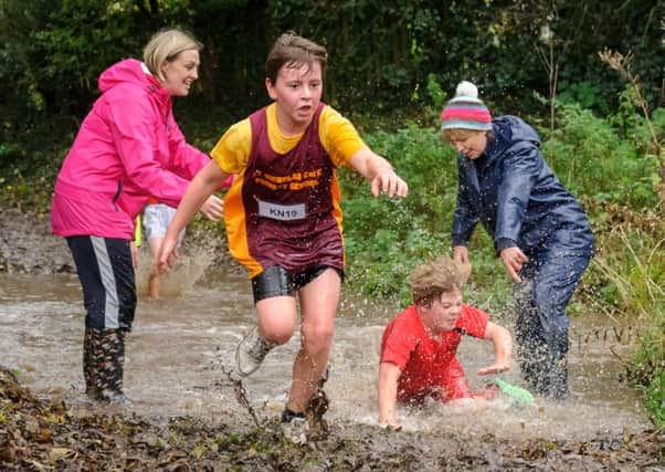 Helpers brave one of the two water features during Saturday's Mid-Warwickshire Primary Schools Cross Country League race at Priors Field. Pictures: MIke Baker