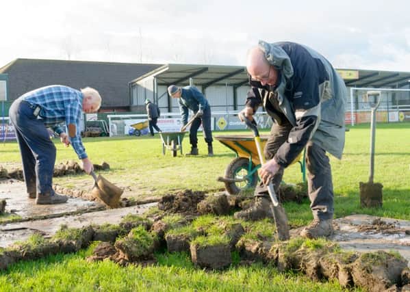 Chairman Jim Scott and groundsman Idris Elms join volunteers in working on the New Windmill pitch. Picture: Mike Baker