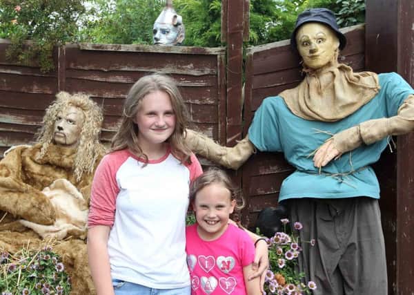 Caitlin Davies, 12 and Paige Davies, 8, next to the Wizard of Oz scarecrows.