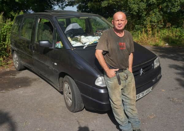 David Reeve next to the car he and his wife live in.