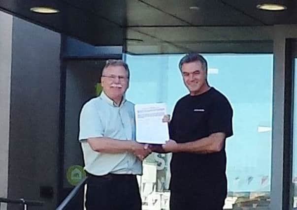 Cllr John Holland receives the petition from Michael Michaels at Shire Hall in Warwick.