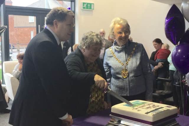 Kate Sayer cutting the cake for the official opening of Sayer Court, joined by Cllr Peter Philips and Chair of Warwick District Council Jane Knight.