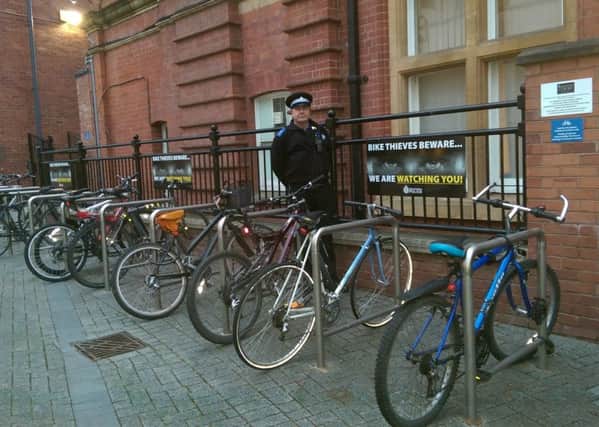 PCSO Steven Sample at the bicycle racks next to Leamington town hall where one of the We Are Watchign You campaign posters has been placed.