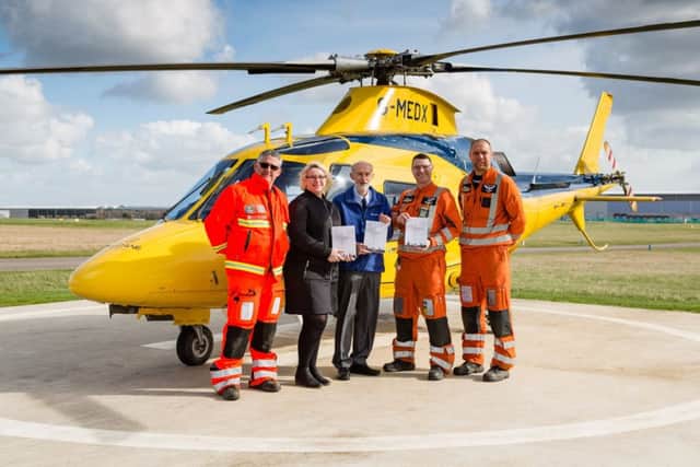 Malcolm Hancock and the Warwickshire and Northamptonshire Air Ambulance crew with his book The History of Rugby Radio Station NNL-170322-125751001